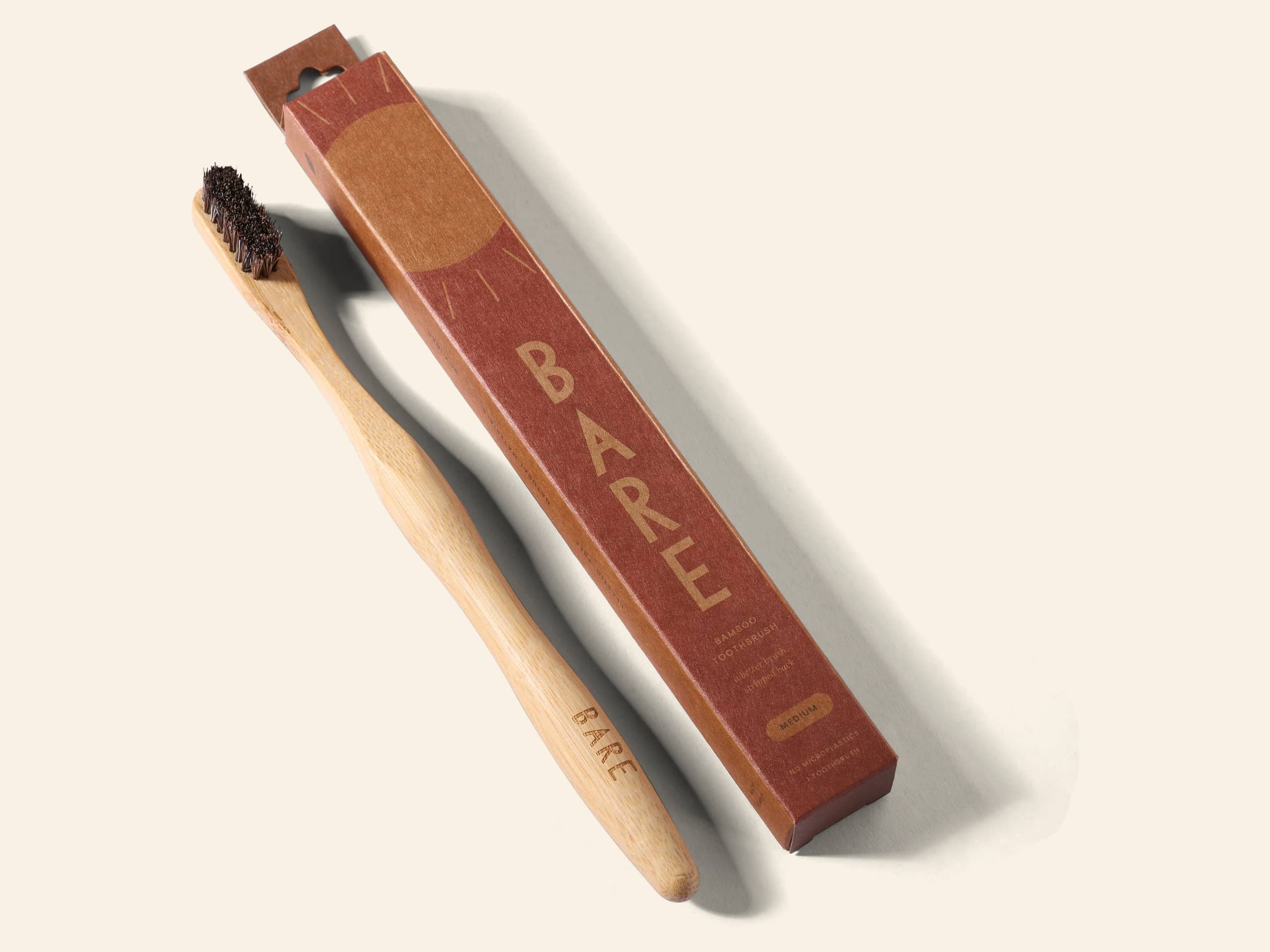 The BARE toothbrush lying beside its kraft pack