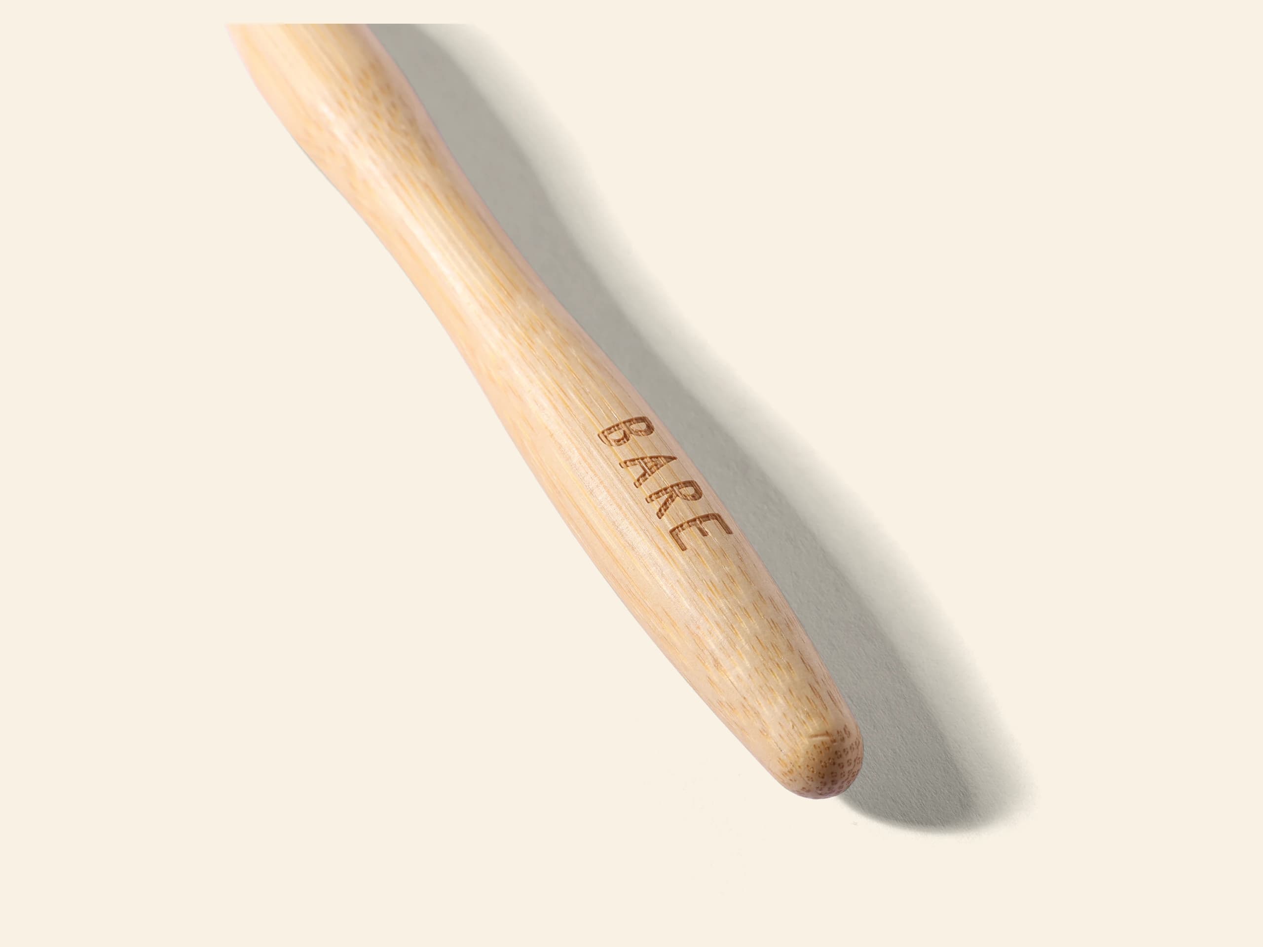 Close-up of a bamboo toothbrush handle with the BARE name engraved into the wood grain.