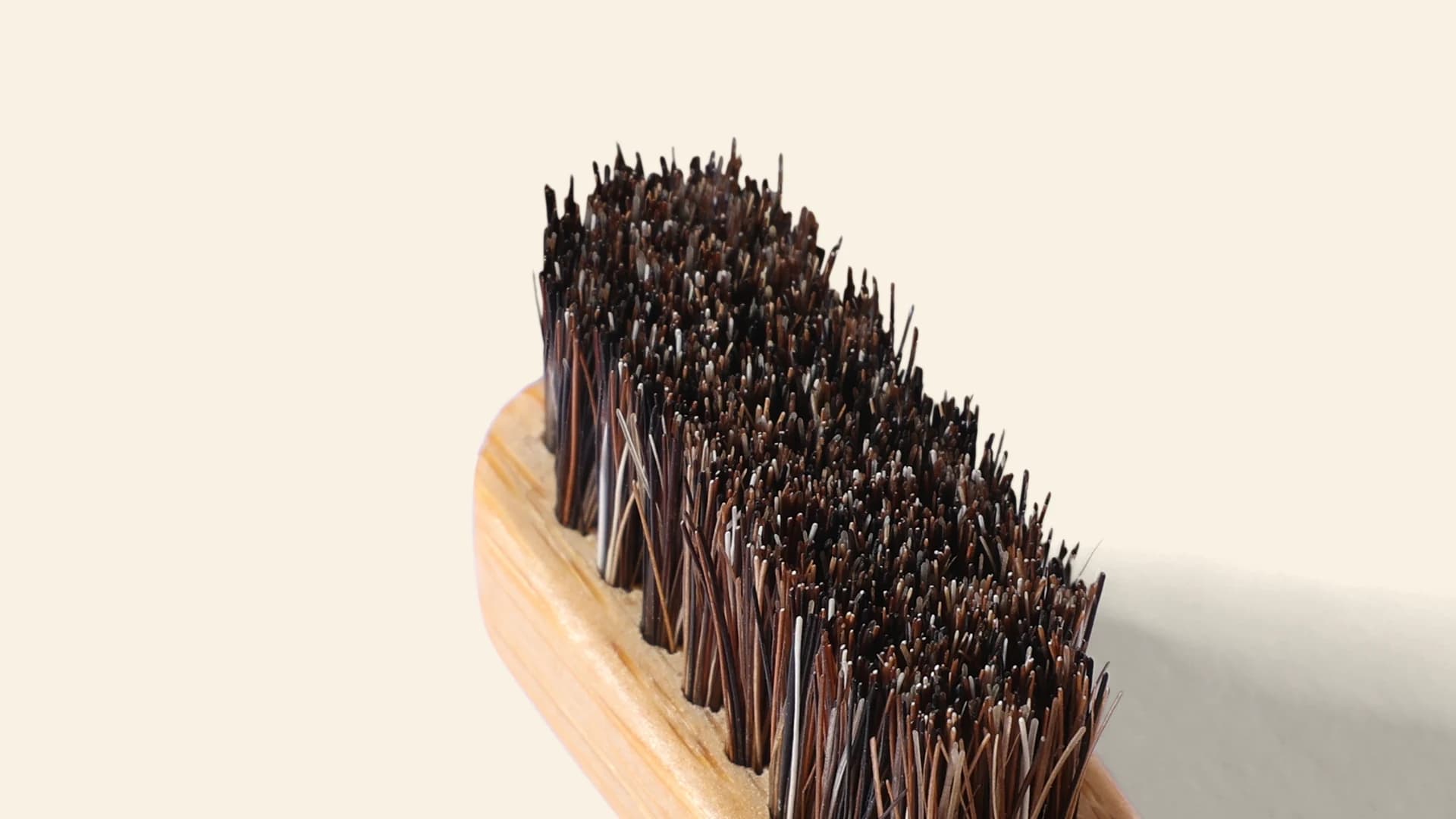 Close-up of a BARE toothbrush head, showing dark horse-hair bristles woven directly into the bamboo with no glue.