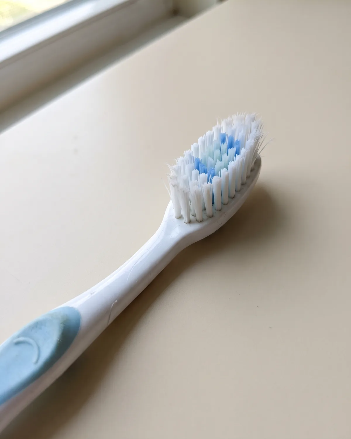 A worn plastic toothbrush with splayed nylon bristles, the tips frayed.